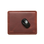Mouse Pad in Chestnut leather with a black wireless mouse, overhead view showing stitched edges