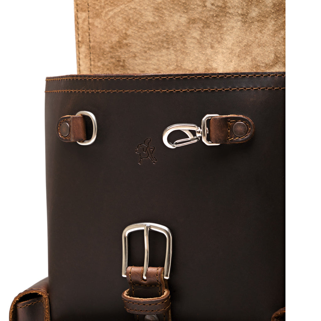 Small Front Pocket Backpack in Dark Coffee Brown, close-up of the front with D-rings, a key clip, a buckle and an embossed logo