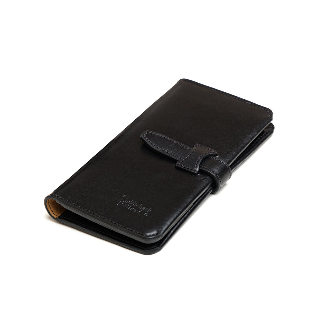 Big Wallet in Raven Black, closed angled view with strap closure and debossed logo
