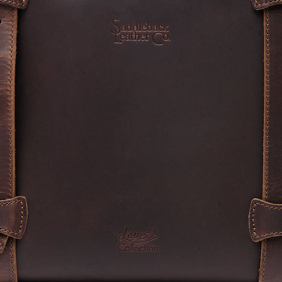 Original Tote in Dark Coffee Brown, close-up of the leather panel with embossed logos and stitched strap loops