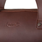 Simple Overnight Leather Duffle Bag in Chestnut, close-up of the embossed Love 41 logo and riveted handle