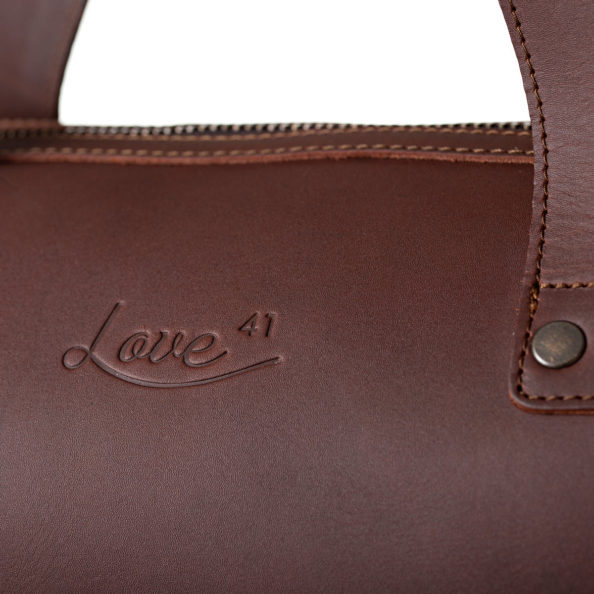 Simple Overnight Leather Duffle Bag in Chestnut, close-up of the embossed Love 41 logo and riveted handle