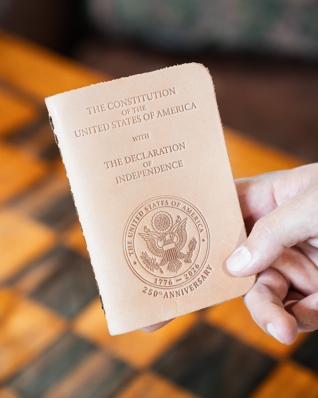 Pocket Declaration/Constitution 250th Limited Edition held in hand above a checkerboard, anniversary seal on the cover