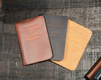 Pocket Declaration/Constitution in Chestnut, black and Tobacco fanned out on a dark wooden table