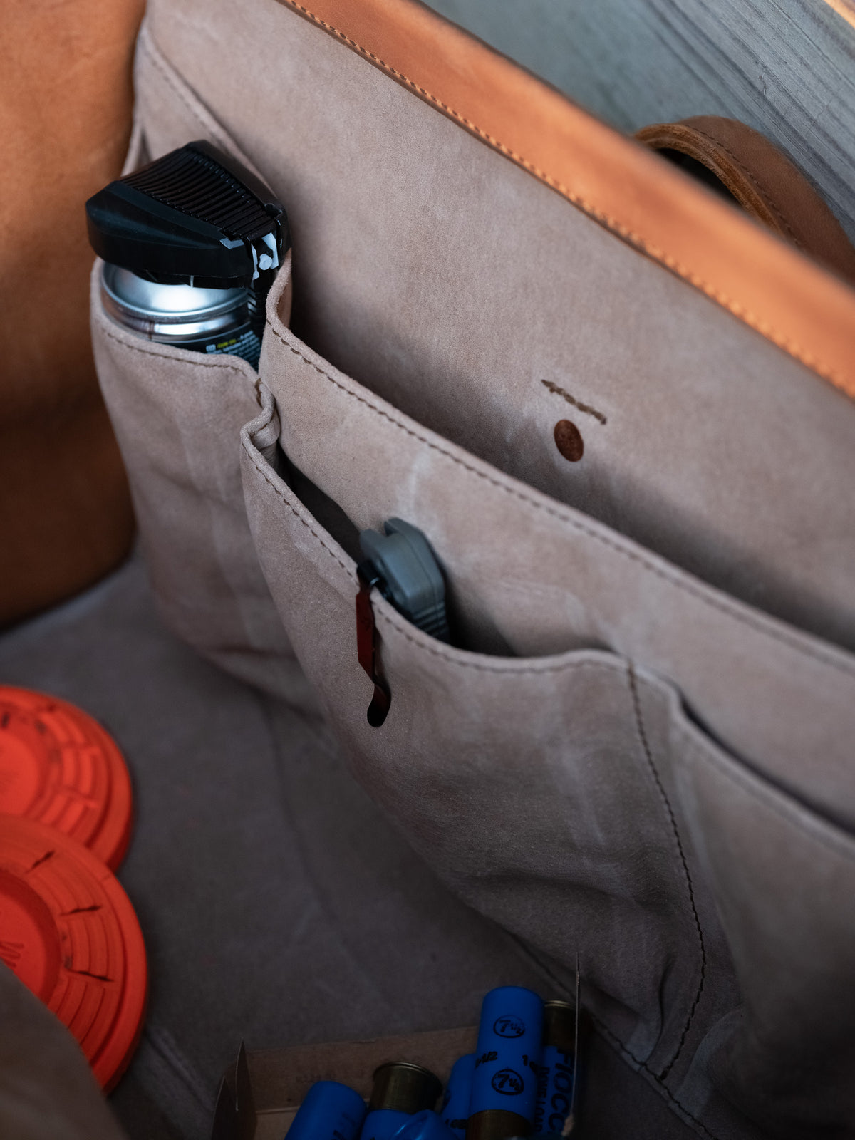 Leather Range and Tool Bag in Tobacco, interior pockets holding a bottle and knife beside clay targets and shotgun shells