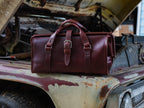Leather Range and Tool Bag in Chestnut on the rusty fender of an old truck with its hood open