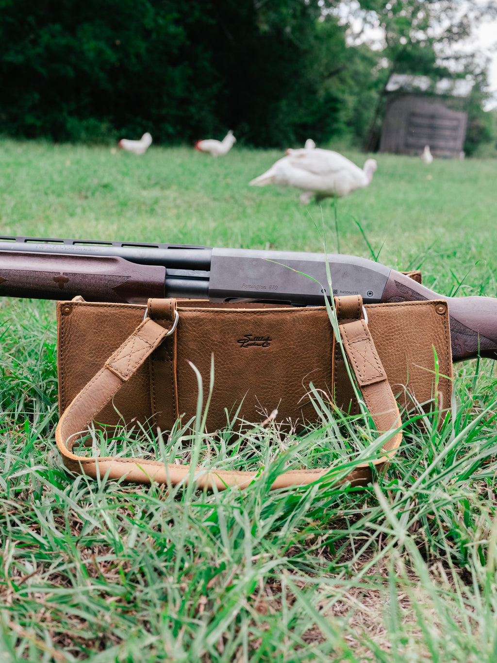 Range and Tool Tote in Tobacco in the grass with a shotgun resting across it and chickens in the background