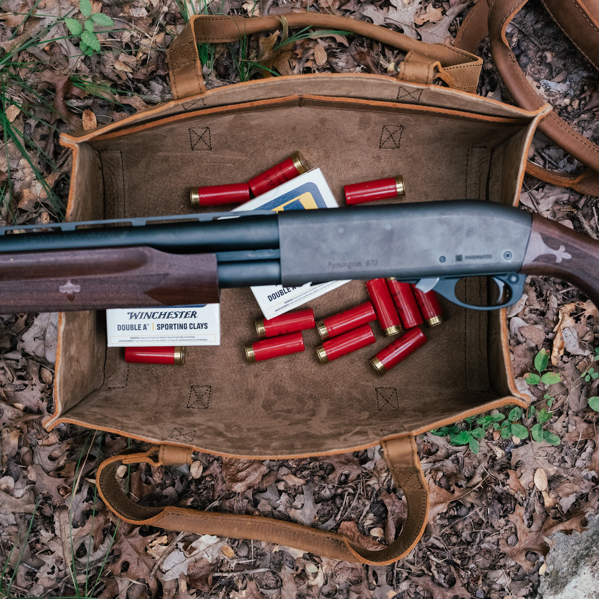 Range and Tool Tote in Tobacco open on fallen leaves, holding a shotgun, shotgun shells and ammo boxes