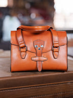 Double Handle Purse in English Tan sitting on a wooden surface in a warmly lit room