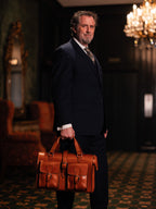 Blackstone Barrister Briefcase in English Tan carried by a man in a three-piece suit in a chandelier-lit room
