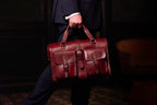 Blackstone Barrister Briefcase in Oxblood carried in mid-stride by a man in a suit in a dim room