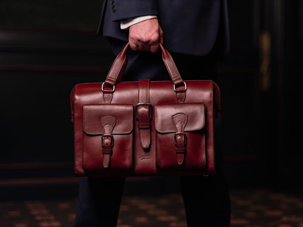 Blackstone Barrister Briefcase in Oxblood carried by its top handles by a man in a dark suit