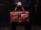 Blackstone Barrister Briefcase in Oxblood carried by its top handles by a man in a dark suit