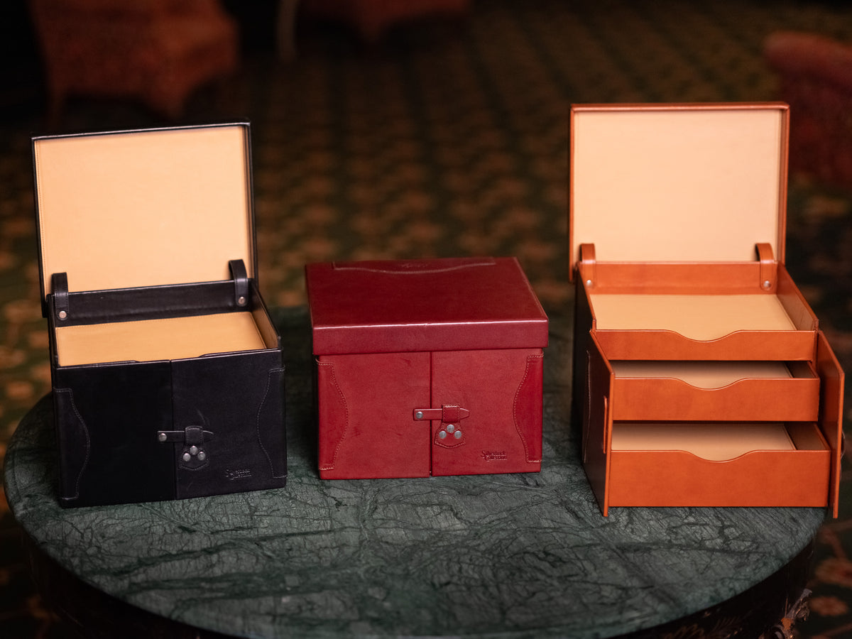 Churchill Case in Raven Black, Oxblood and English Tan side by side on a marble table, two shown open