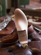 Shoe Tree standing upright on its heel in front of brown wingtip shoes