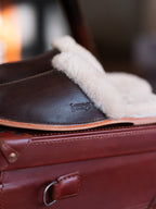 Men's Sheepskin Slippers in Dark Coffee Brown, close-up side view of embossed logo and sheepskin cuff