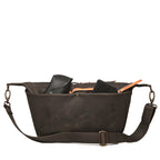 London Sling Large in Black, front view with a phone and glasses case peeking from the open top