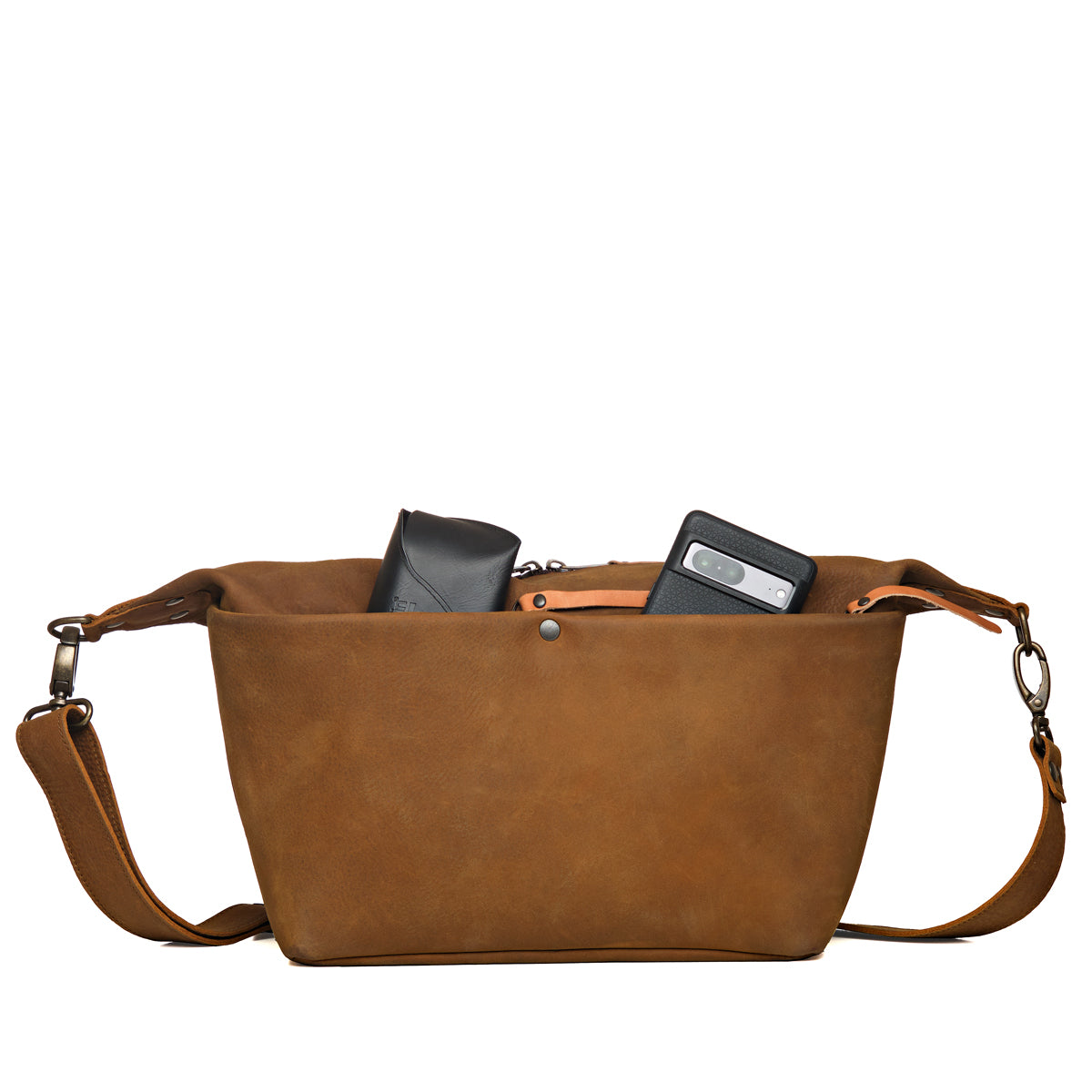 London Sling Large in Tobacco, front view with a phone and glasses case peeking from the open top