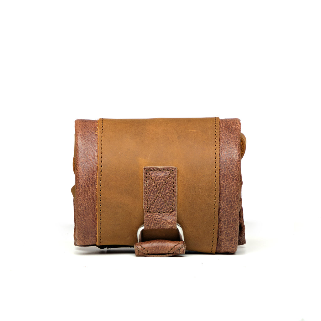 Travel Tote in Burnt Sausage, rolled up for packing and secured with its leather strap and D-ring