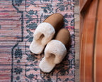 Women's Sheepskin Slippers in Tobacco, top-down view of pair on a patterned woven rug