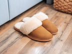 Women's Sheepskin Slippers in Tobacco, pair with fluffy sheepskin cuffs on a hardwood floor