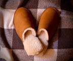 Pair of Women's Sheepskin Slippers in Tobacco on a checkered blanket, top view