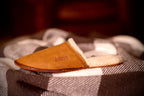 Women's Sheepskin Slipper in Tobacco resting on a checkered blanket, side view