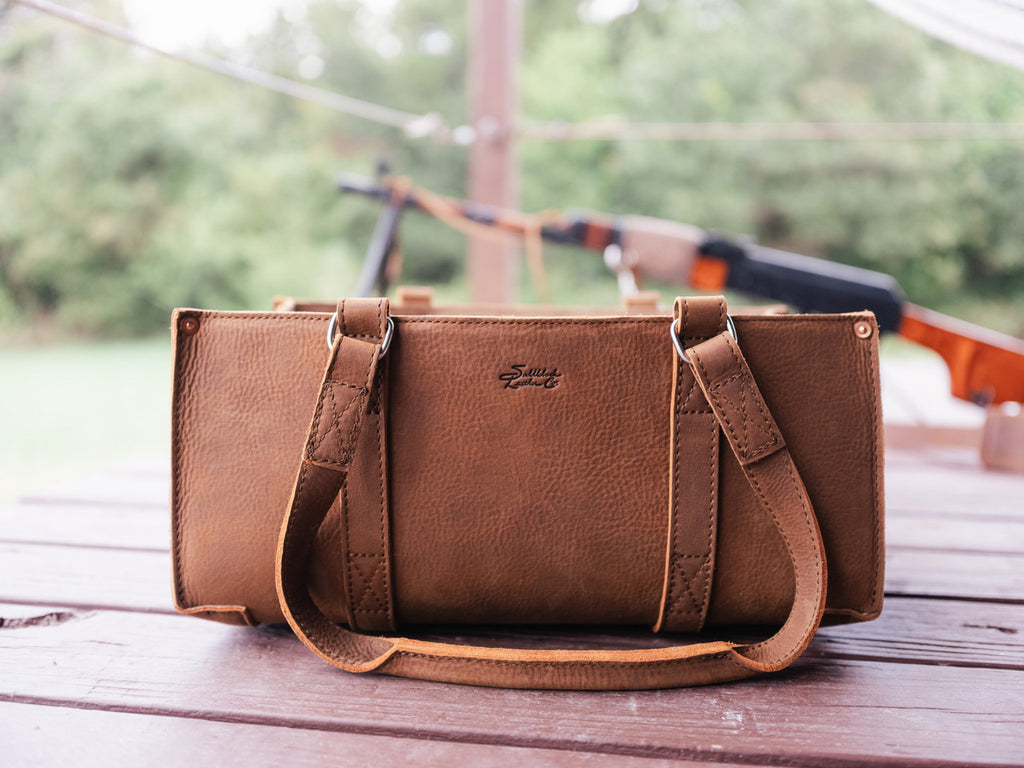 Range and Tool Tote in Tobacco on a wooden deck with a rifle blurred in the background