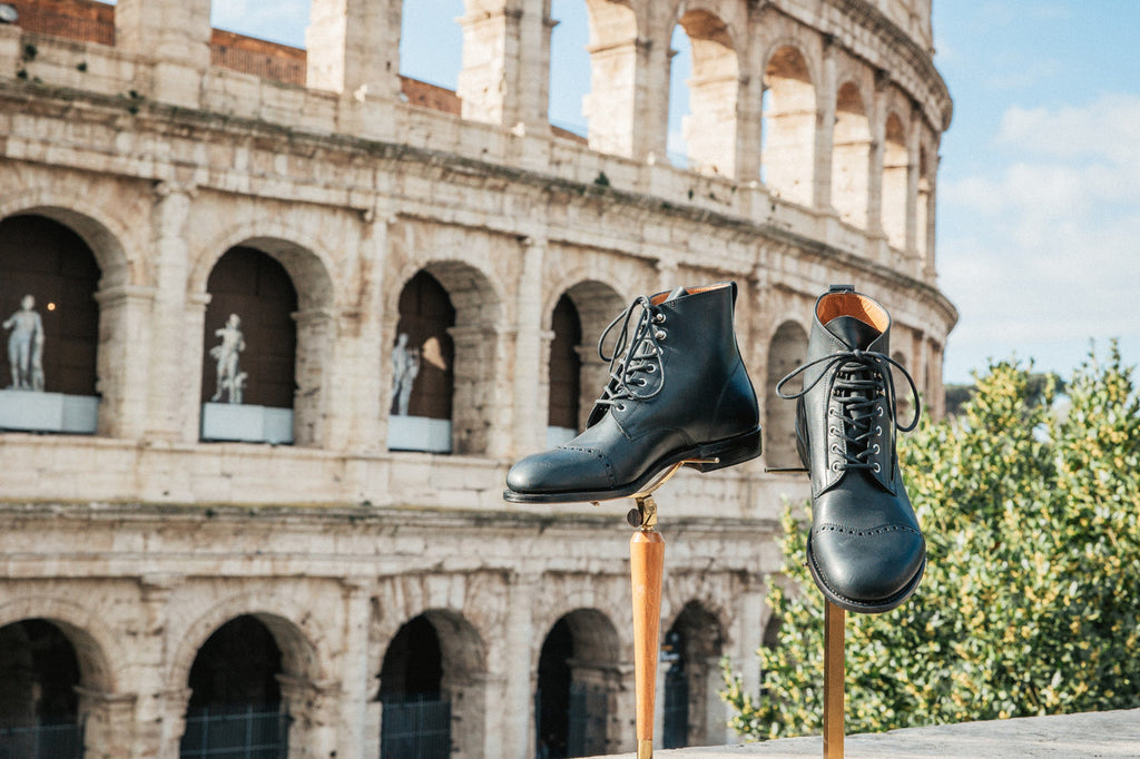 Pair of high quality black leather Officer Boots on stands in front of the Colosseum in Rome