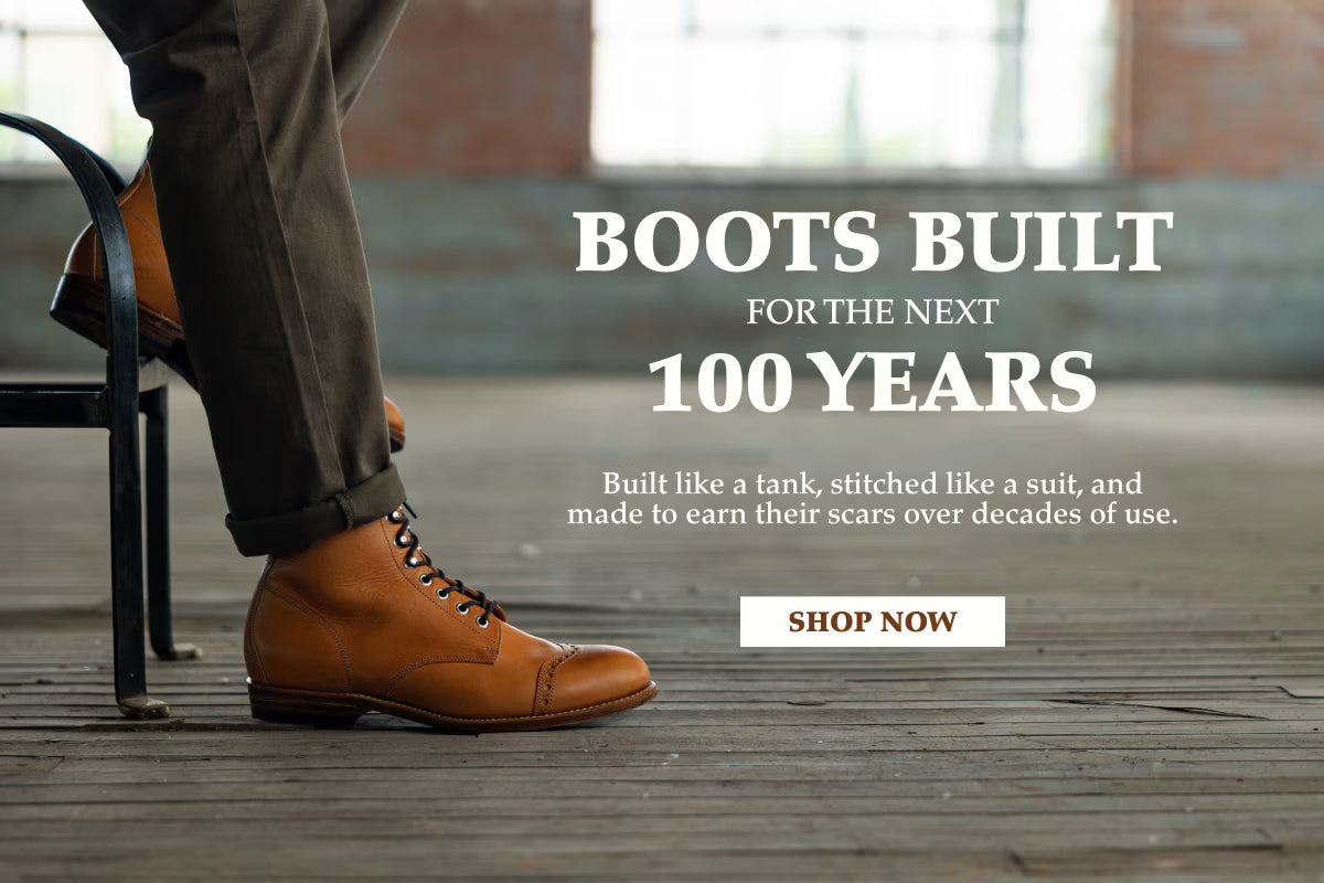Boots built for the next 100 years. Built like a tank, stitched like a suit, and made to earn their scars over decades of use. Shop now. A tan leather cap-toe boot resting on a weathered wooden floor.