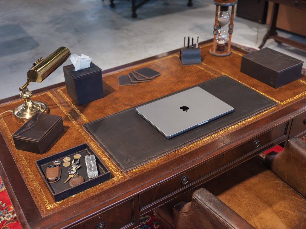 Long Desk Pad in Dark Coffee Brown on an antique desk with a laptop, brass lamp, hourglass and leather desk accessories