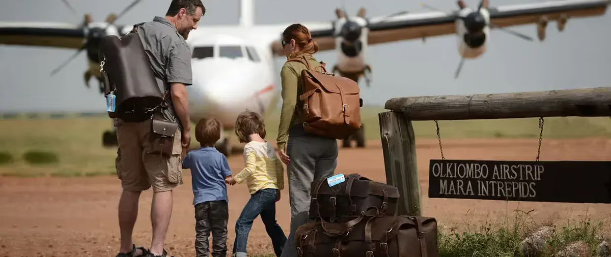 Family with leather backpacks and duffle bags walking toward a small plane at the Olkiombo Airstrip in the Maasai Mara