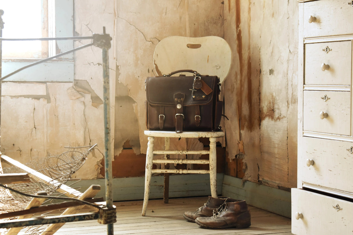 Dark Coffee Front Pocket Leather Briefcase on a white wooden chair in a rustic room
