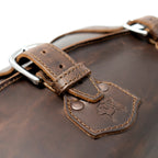 20" Waterbag in Dark Coffee Brown, close-up of steel buckle and riveted tab stamped with the dog logo