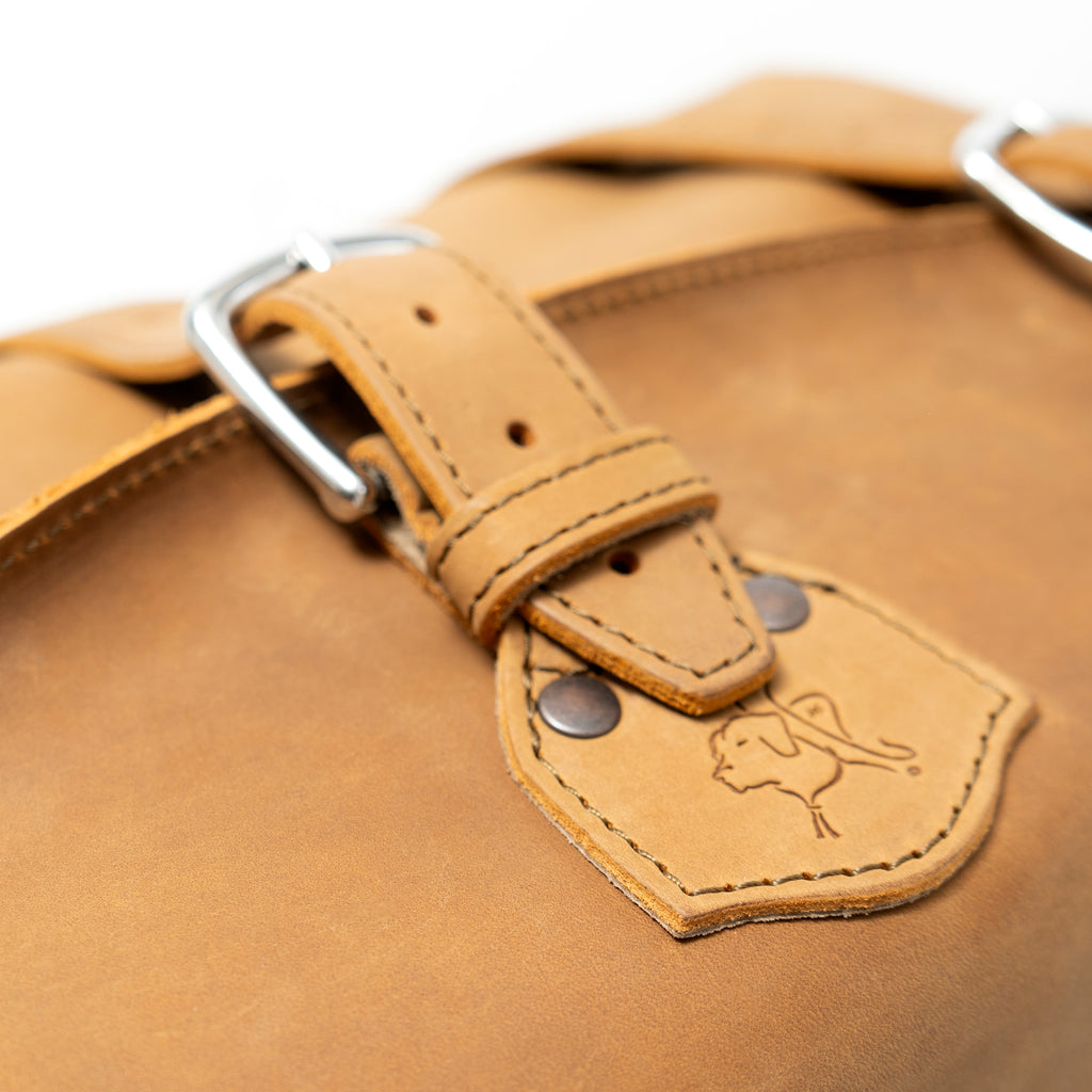 20" Waterbag in Tan, close-up of steel buckle and riveted tab stamped with the dog logo