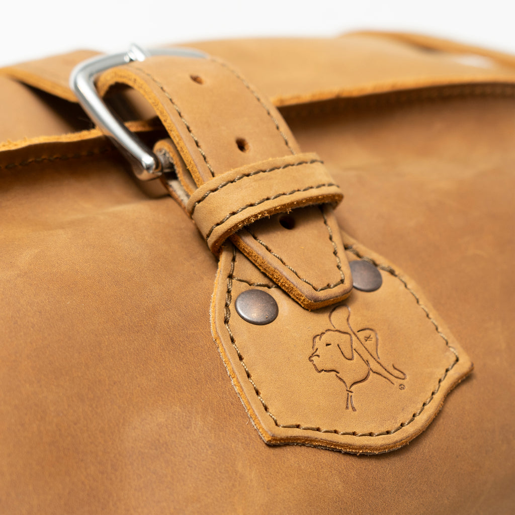 24" Waterbag in tan, close-up of a buckle strap and riveted tab with embossed pig logo