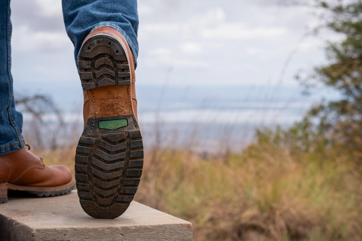 Rear view of a high quality natural tan leather Huntsman Boot raised to show the lug sole tread outdoors