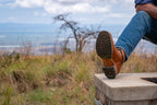 High quality natural tan leather Huntsman Boot stepping over a stone ledge, sole view of the lug tread