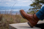 High quality natural tan leather Huntsman Boot mid-step on a stone ledge, heel raised to show the lug sole