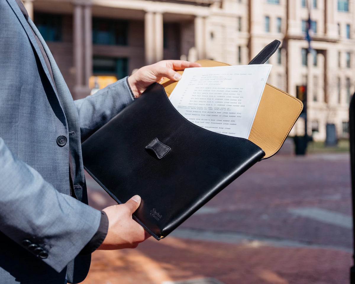 Silverback Document Holder in Raven Black held open by a man in a grey suit, pulling out papers on a city street
