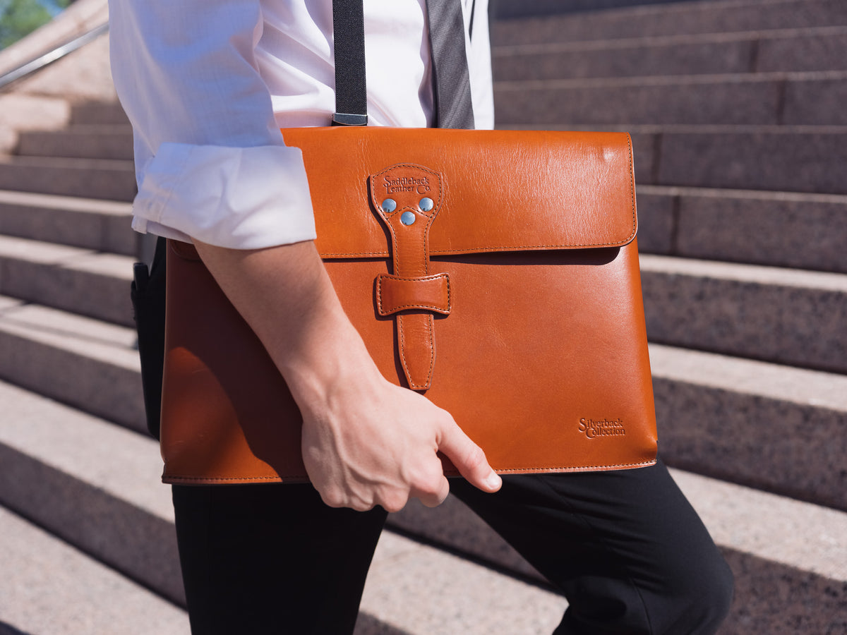 Silverback Document Holder in English Tan carried at the side by a man in a white shirt walking up stone steps