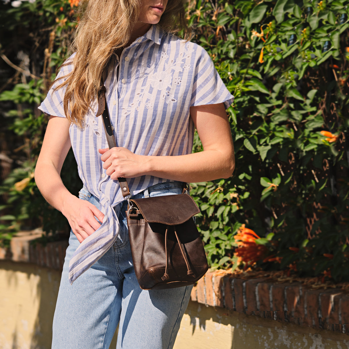 Mini Bucket Bag in Dark Coffee Brown, worn crossbody by a woman in a striped shirt outdoors