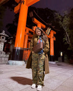 London Sling Small worn crossbody by a woman standing before orange torii gates at night