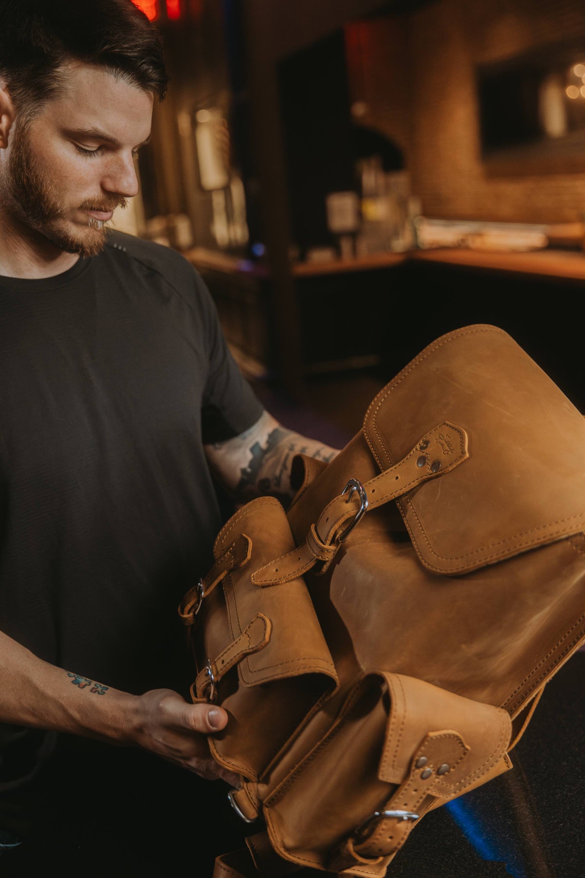 Jonah Heim opening the flap of a tan leather backpack.