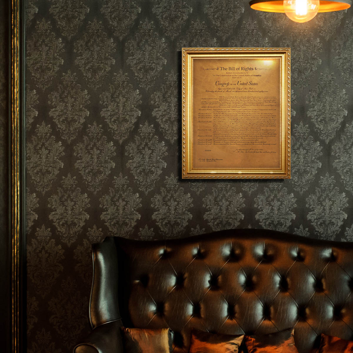 Leather Bill of Rights in a gold frame, hung on damask wallpaper above a tufted leather sofa