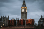 Three Grandfather Carry On suitcases in brown leather lined up on a ledge in front of Big Ben
