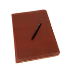 Old Design Medium Leather Portfolio in Chestnut, closed and angled with a pen resting on the cover