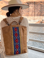Lanita Leather Backpack in tan, worn by a woman in a wide-brim hat on a boat by canyon walls