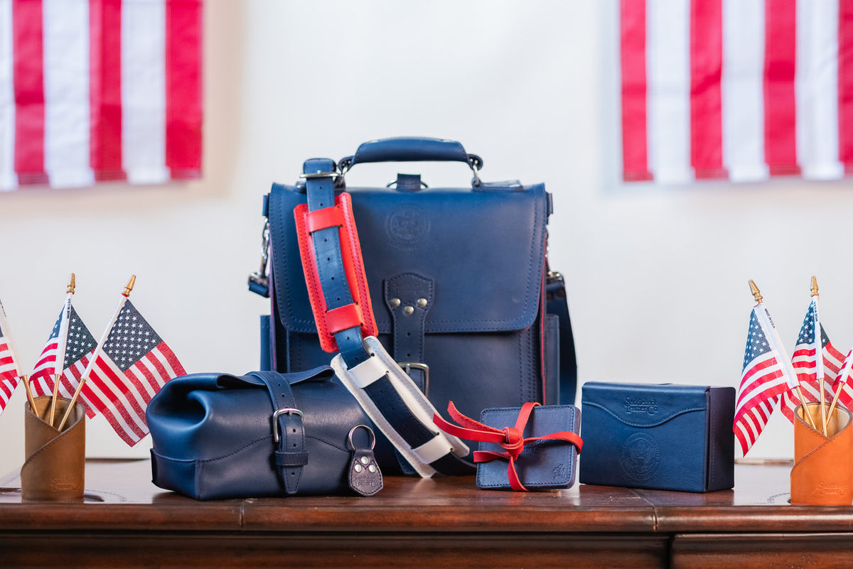 2026 Membership Bundle: high quality navy blue leather bag and accessories with red straps on a table with American flags