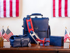 Saddleback Club Membership 250th Anniversary collection in Blue and Red on a wood desk among small American flags